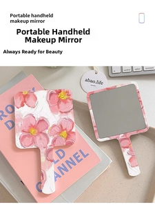 Close-up of portable hand mirror featuring vintage pink floral oil painting texture