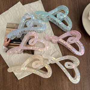 Set of 6 iridescent heart-shaped hair claw clips in pearlized resin on wooden desk