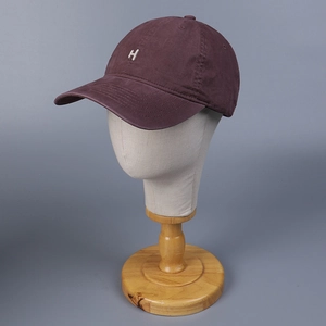 Detail of white H letter embroidery on washed cotton deep purple baseball cap texture