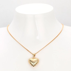 Close-up of gold hollow heart pendant with radiating texture on model's neck