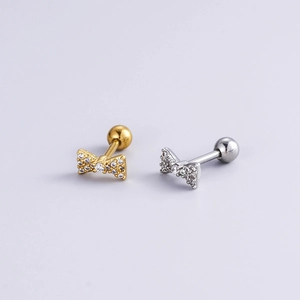Detailed view of gold and silver bow stud earrings with sparkling zircon crystals