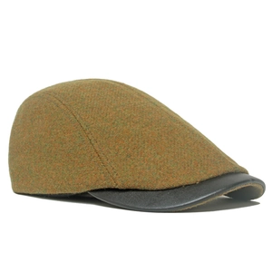 Close-up of vintage wool tweed flat cap featuring a premium black leather brim detail