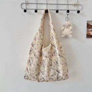 Detailed close-up of floral embroidery and lace mesh overlay on a beige tote bag