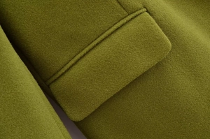 Dettaglio del cappotto di lana verde oliva con tasca a patta e trama del tessuto fitta