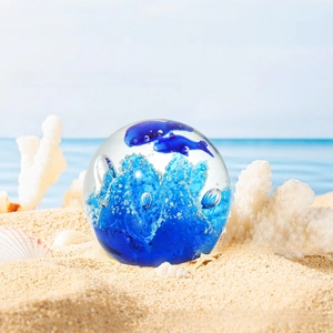 Macro detail of crystal ball with blue dolphin and artistic coral swirl on beach
