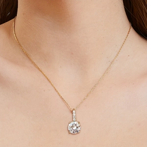 Gold-plated necklace featuring a round four-claw cubic zirconia pendant on a female model