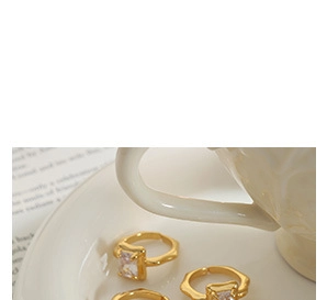 Detailed view of three vintage gold rings with rectangular zircon on a ceramic dish
