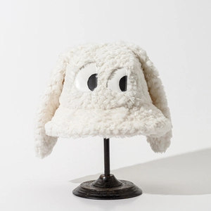 Détail d'un chapeau bob en peluche blanche avec de longues oreilles et broderie yeux