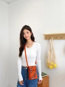 Detail of trendy orange knitted mini crossbody bag shown on model with casual outfit