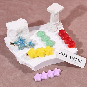 Macro view of pastel resin star hairpins on white wave textured display base
