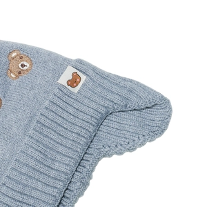 Détail du bonnet en tricot bleu clair avec broderie ours et petite étiquette tissée