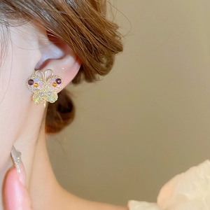 Detail of butterfly earring with purple and amber crystals on gold-plated needle