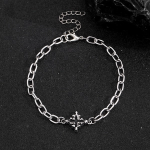 Hip-hop silver metal chain bracelet with black enamel cross pendant on dark surface