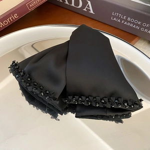 Close-up of black satin bow hair claw clip with exquisite crystal beaded edge and silky texture