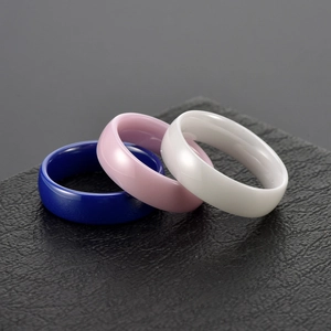 Minimalist ceramic rings in blue, pink, and white on a premium black display stand