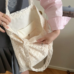 Detail of white lace mesh tote bag showing the spacious interior and zipper pocket