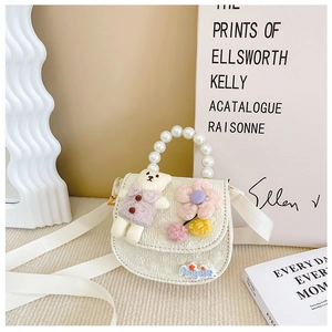Detail of child handbag with plush bear, pearl handle, and colorful floral ornaments