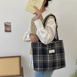 Macro view of vintage plaid wool tote bag showing textured fabric and white brand label