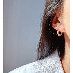 Minimalist gold hoop earrings with embossed texture shown on a female model