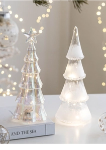 Macro shot of glass Christmas trees with LED warm lights, iridescent and frosted finishes
