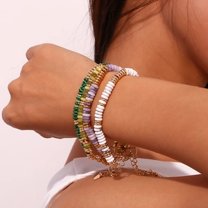 Detail von vier böhmischen Perlenarmbändern in Grün, Lila und Weiß mit goldenen Trennelementen