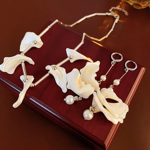 Dettaglio parure con collana a fiore bianca e orecchini di perle su scatola di legno