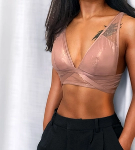 Detail of rose gold metallic sports bra featuring a deep V-neck and crisscross hem design