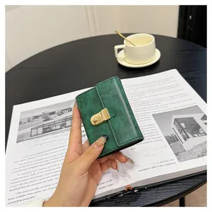 Close-up of a dark green leather wallet with gold buckle on a stylish cafe table