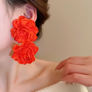 Close-up of double-layered orange fabric flower drop earrings with silk texture and details