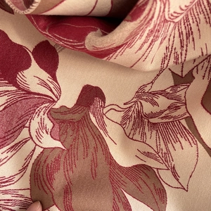 Close-up of beige cashmere-like scarf fabric with elegant red magnolia floral print