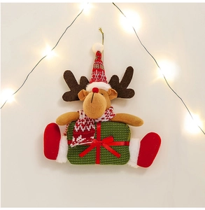 Plush Christmas reindeer ornament with red knit hat sitting on a green gift box decoration