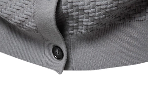 Macro shot of dark grey knit cardigan showing fine texture, hem and black round button