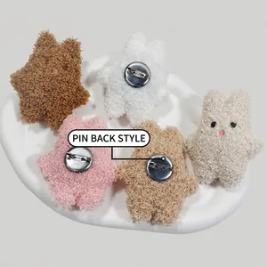 Plush star-shaped brooches in five colors with metal safety pins on a ceramic plate