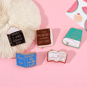 Detailed view of five creative book-shaped enamel lapel pins on a pink artistic background