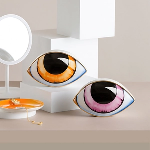 Detail of high-gloss ceramic evil eye ornaments with orange and pink iris and gold trim