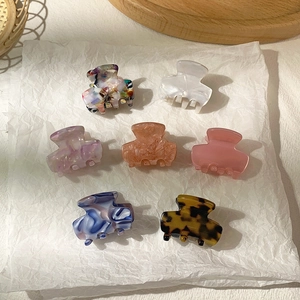 Detailed flat lay of small acetate hair claws in marble and leopard patterns on white paper