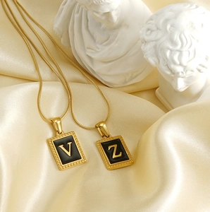 Detail of 18K gold-plated square initial pendants V and Z on elegant champagne satin
