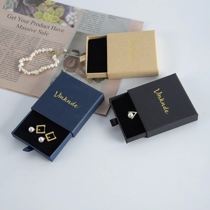 Three drawer jewelry gift boxes in black, navy and kraft colors on newspaper background