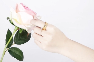 Detail of vintage gold stainless steel rings with rhinestones on hand with pink rose