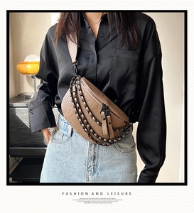Detail of brown crocodile pattern chest bag with black metal chains and wide strap