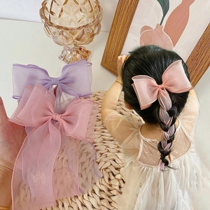 Detailed view of pink and purple organza ribbon hair bows on a girl's braided hair