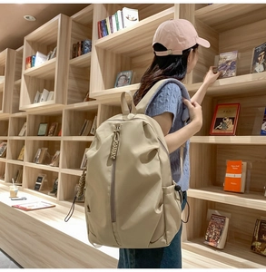 Close-up of beige nylon backpack with woven zipper details against wooden bookshelves