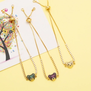 Détail de bracelets ours ajustables avec zircons colorés présentés sur un fond jaune vif