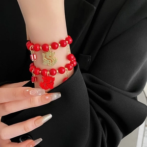 Gros plan d'un ensemble de bracelets en perles rouges avec breloques dragon or et rouge