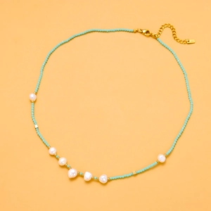 Detail of green beaded necklace with baroque pearls and gold lobster clasp finish