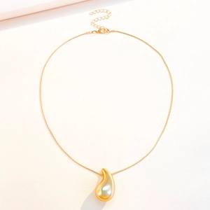 Detailed close-up of golden teardrop pendant on a sleek snake chain necklace