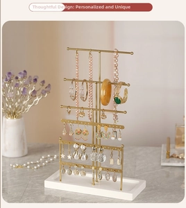 Detail of 6-tier gold jewelry stand with earring holes and solid white base tray