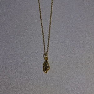 Detailed close-up of golden conch shell pendant on a delicate O-chain necklace