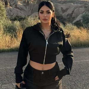 Outdoor shot of a black zip-up cropped hoodie for women with a scenic mountain background