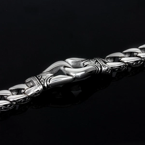 Close-up of vintage engraved silver chain bracelet with intricate totem patterns on black surface